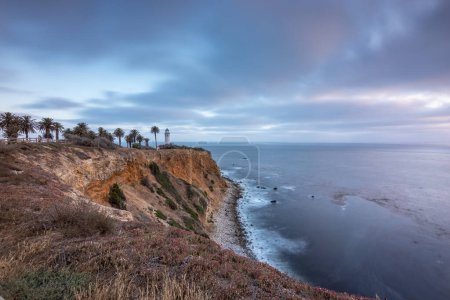 Tranquilo atardecer pinta el cielo sobre Point Vicente, proyectando tonos dorados sobre la escarpada costa, un momento sereno en Rancho Palos Verdes, California.