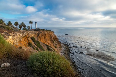 Beautiful coastal view of Point Vicente Lighthouse atop a tall cliff with ocean waves crashing into the rocky shoreline below, Rancho Palos Verdes, California