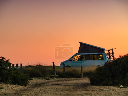 Camioneta autocaravana con carpa en la azotea acampando en la costa mediterránea. Vacaciones y viajes en autocaravana.