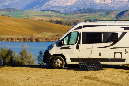Portable solar panel at camper van camping on nature, lake Embalse del Guadalhorce, Ardales Reservoir, Malaga province in Andalusia, Spain.