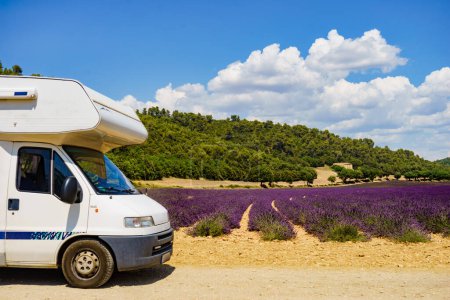 Camper vehicle camping on summer nature at lavender blooming purple field in France. Holidays, vacation with mobile home.