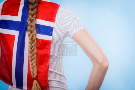 Chica rubia trenza el pelo con bandera noruega en la espalda. Gente escandinava.