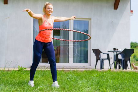 Frau mit Hoola-Reifen für schlanke Taille, Übungen Fitness-Studio im Freien im Garten. Workout Sport und Training.