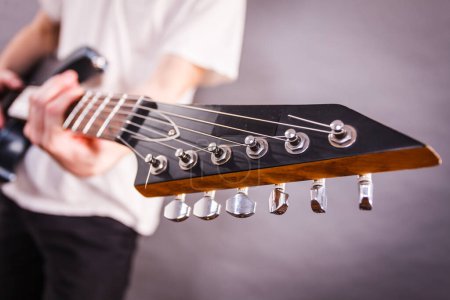 Close up on guitar fretboard of man playing electric guitar during gig or at music studio. Musical instruments, passion and hobby concept.