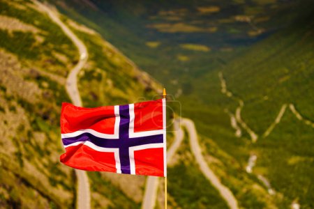 Norwegian flag and Trolls Path Trollstigen winding scenic mountain road in Norway Europe (en inglés). Ruta turística nacional.