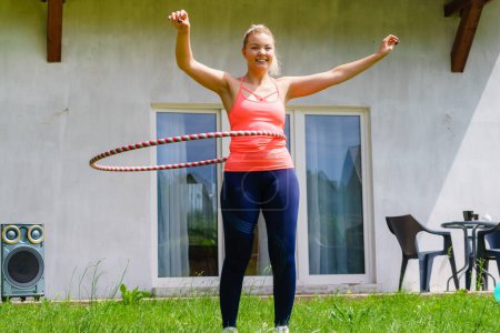 Frau mit Hoola-Reifen für schlanke Taille, Übungen Fitness-Studio im Freien im Garten. Workout Sport und Training.