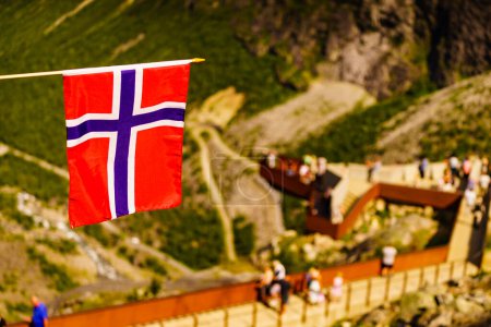 Trollstigen paisaje de carretera de montaña en Noruega, Europa. Bandera noruega ondeando y muchos turistas personas en la plataforma de visualización en segundo plano. Ruta turística nacional.