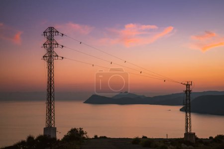 Coastline at sunset with electricity transmission pylons, power lines high voltage towers. Mesa Roldan, Cabo de Gata, Spain.