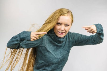 Angry young woman pointing with fingers. Frustrated face expression, hair blowing.