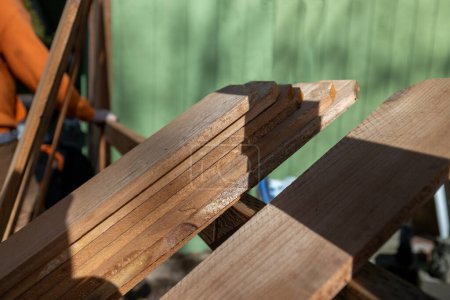 Photo for Wood Pickets Sit Along Fence Backer Rails as Worker Prepares to Build Cedar Barrier for a Home Upgrade - Royalty Free Image