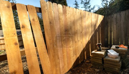 Photo for Building a Cedar Picket Wood Fence Scene Stringers Backer Rails  No People Box of Screws Power Tools Screwdriver Framing Square - Royalty Free Image