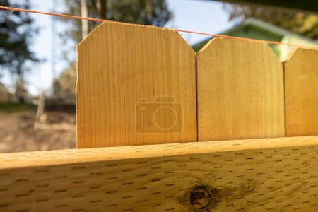 Foto de Primer plano de la cuerda espaciada a lo largo de la parte superior de los piquetes de cedro de madera en la nueva valla Construir mejora de patios de bricolaje - Imagen libre de derechos