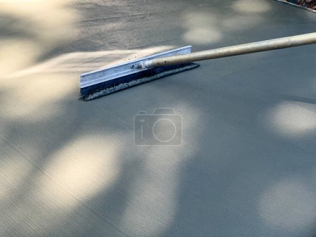 Téléchargez les photos : Balai de béton texturé brossant une surface fraîchement coulée - en image libre de droit