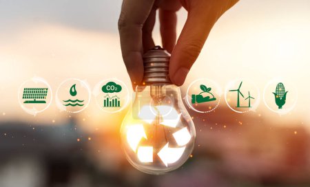 Hand holding light bulb with recycle symbol inside against with icons energy sources for renewable, sustainable development. natural energy and love the world concept.
