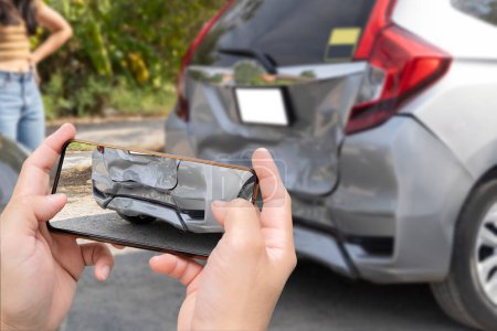 Téléchargez les photos : Woman holding smartphone and taking picture of car accident. Car insurance and payout concept, damaged vehicles with a smartphone as a proof of insurance claim. - en image libre de droit