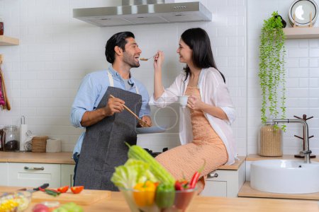 Téléchargez les photos : Un jeune couple amoureux s'amuse en préparant un petit déjeuner ensemble par une belle matinée. Cuisine, ensemble, cuisine, relation. La femme qui nourrit l'homme - en image libre de droit