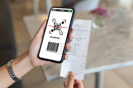 Photo for Asian woman paying electricity bill hand holding smart phone scanning code on paper, scan the qr code. Scan to get discounts. Using a phone to transfer money, paying money online without cash concept. - Royalty Free Image