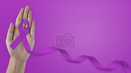 Foto de Atención médica, concepto de seguro. Manos sosteniendo cinta púrpura o violeta en tela blanca con espacio para copiar. Cáncer de páncreas, Conciencia sobre el cáncer testicular, Sobreviviente de cáncer, Leiomiosarcoma, Día Mundial del Cáncer. - Imagen libre de derechos