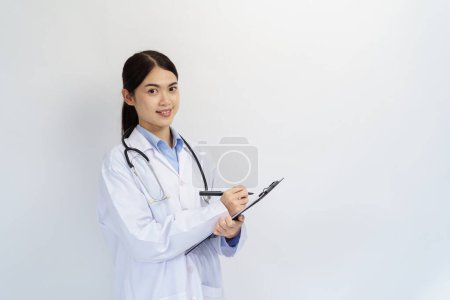 Photo for Concept of doctor and medical. Asian female Doctor hand taking note information of patient in paperwork checklist on clipboard with blue background. - Royalty Free Image