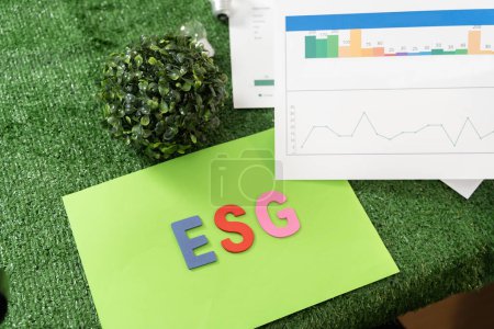 Green paper with the word "ESG" written on it. The paper is green and has a graph on it. The graph shows three lines, one for each of the three ESG factors: environment, social, and governance.