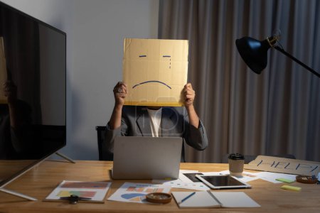 Photo for Portrait of businessman covering his face with paper mask with sad face drawn on it, bad negative sullen depression anonymouse person. - Royalty Free Image