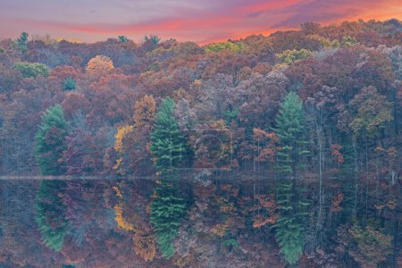 Téléchargez les photos : Autumn landscape at dawn of the shoreline of Hall Lake flocked with snow and with mirrored reflections in calm water, Yankee Springs State Park, Michigan, USA - en image libre de droit