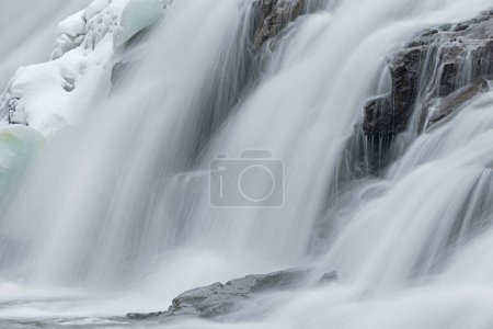 Winter, Bond Falls captured with motion blur and framed by ice and snow, Michigan's Upper Peninsula, USA