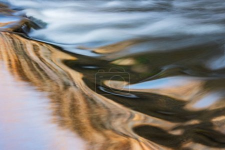 Téléchargez les photos : Paysage des rapides du ruisseau Portage capturé avec flou et éclairé par la couleur réfléchie des arbres éclairés par le soleil et le ciel bleu au-dessus, Michigan, États-Unis - en image libre de droit