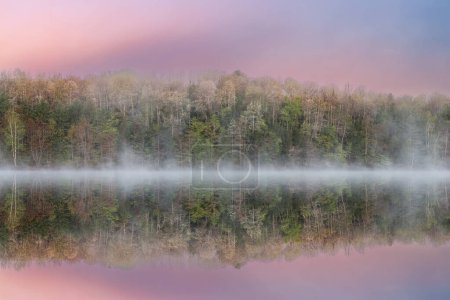 Paisaje de primavera brumoso al amanecer del lago Mocasín con reflejos reflejados en aguas tranquilas, Bosque Nacional Hiawatha, Península Alta de Michigan, EE.UU.
