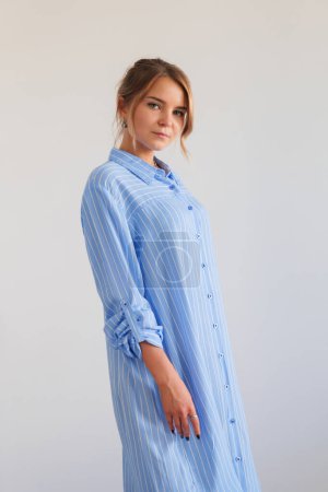 Young woman wearing ink and blue striped oversized summer shirt. Trendy casual outfit. 