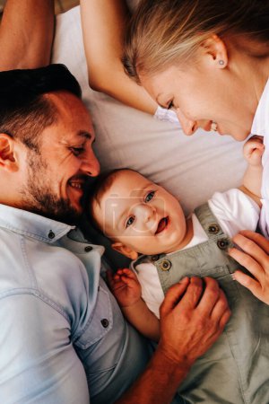 Foto de Joven familia feliz. Cuidado jóvenes padres caucásicos jugando con su pequeño bebé lindo en la sala de estar - Imagen libre de derechos