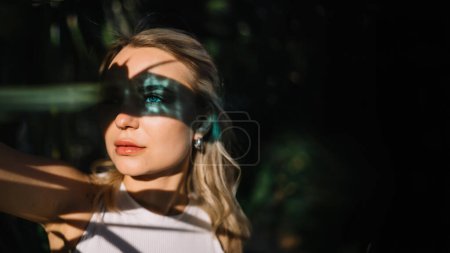 Striking portrait of a beautiful attractive young blonde woman with blue eyes with blue reflections on face skin. Beautiful light effect from blue glass in sunny day