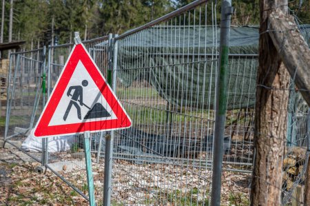 Photo for Construction area with german red triangle shape sign standing next to a metal fence - Royalty Free Image
