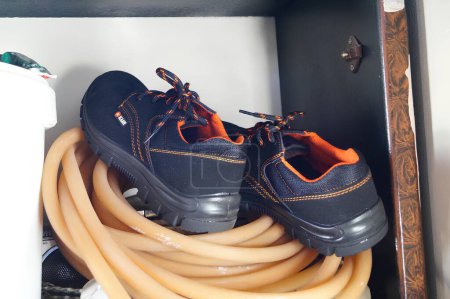 Ein Paar Stiefel, die auf einem aufgerollten orangefarbenen Schlauch in einem Schrank ruhen