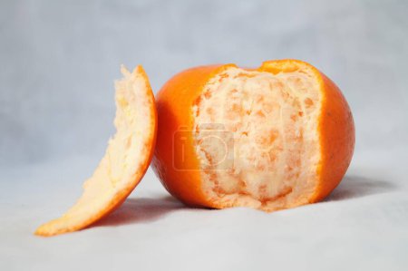 Eine geschälte Orange mit einem Biss aus ihr herausgenommen. Hochwertiges Foto