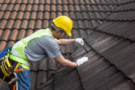 Foto de Hombre trabajador que utiliza la reparación de recubrimiento de techo resistente al agua para fijar la grieta del techo de baldosas viejo. - Imagen libre de derechos