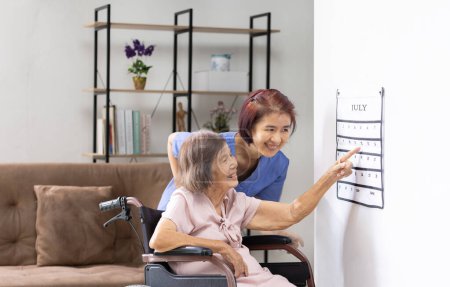 Asiatische Seniorin liest Kalendertherapie-Übungen von Demenzkranken mit Pflegerin.