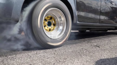 Arrastre coche de carreras quema neumático en la línea de partida en pista de carreras