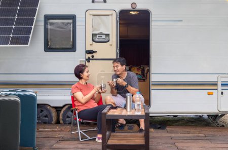 Senior asiático pareja alegre y relajarse sentado en frente de caravana casa de vacaciones.