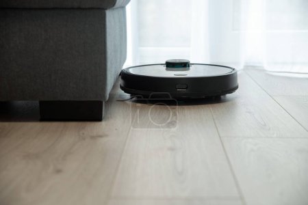 Photo for Robot vacuum cleaner is cleaning floor, top view - Royalty Free Image