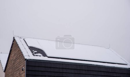 Techo de una casa con paneles solares cubiertos de nieve