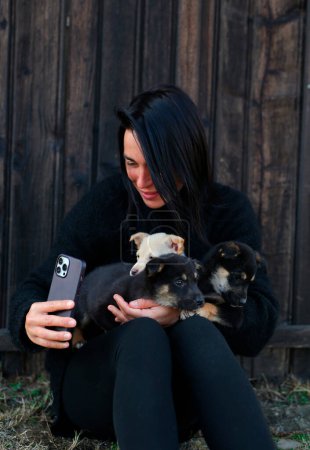 Photo for A girl of thirty is holding homeless puppies in her hands, a woman is a volunteer, she helps the puppies, takes care of them, takes a photo for them to attach the puppies to families. national puppy day - Royalty Free Image