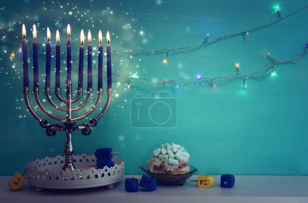 Photo for Image of jewish holiday Hanukkah background of menorah (traditional candelabra), doughnut and candles. Spinning tops with letters that mean, a great miracle happened here - Royalty Free Image