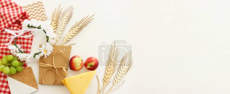 Photo of dairy products over wooden white background. Symbols of holiday - Shavuot