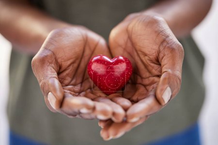 Foto de Acercamiento de manos de mujer negra sosteniendo un pequeño corazón rojo. Pequeño corazón en las manos de una mujer africana. Concepto de solidaridad, caridad y responsabilidad. - Imagen libre de derechos