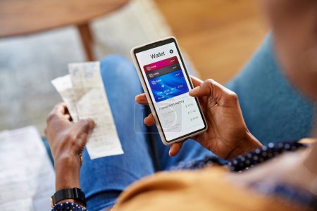 Photo for Hands of african american woman using mobile phone to check payments, account statement and transaction history. Close up of black woman hand using smartphone for checking the balance of her online wallet. Checking expenses of the month on smart phon - Royalty Free Image