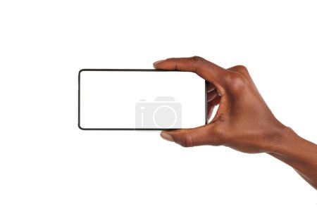 Photo for Close up of african american woman hand showing smartphone against white background horizontally. Black woman holding with one hand cellphone with empty screen. Closeup of mobile phone with blank screen isolated on white background. - Royalty Free Image