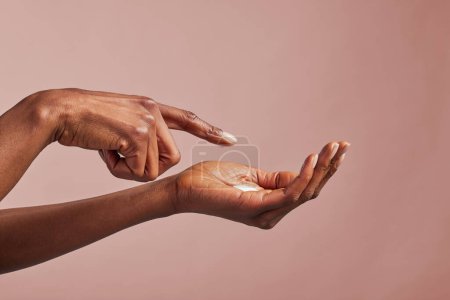 Photo for Elegant female hands with moisturizing cream closeup. Black woman applying organic cream on hands isolated on brown background. Close up shot of beautiful female hands holding and applying nourishing cream - Royalty Free Image