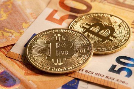 Photo for Two golden bitcoin coins over fifty euro banknotes. Invest in bitcoin cryptocurrency to edge inflation. Exchange your money into decentralized digital currency. - Royalty Free Image