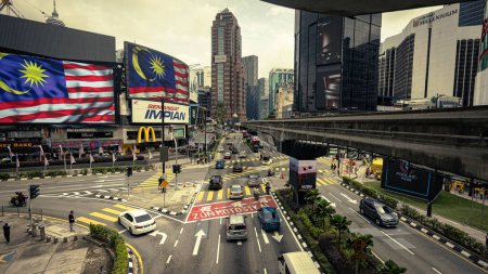 Foto de Kuala Lumpur, Malasia - 21 de agosto de 2022: Intersección de Bukit Bintang. Imagen HDR de larga exposición del ajetreado cruce en el centro de la ciudad de KL. Coches y motocicletas pasando, la pista de la cruz del monorriel por encima. - Imagen libre de derechos